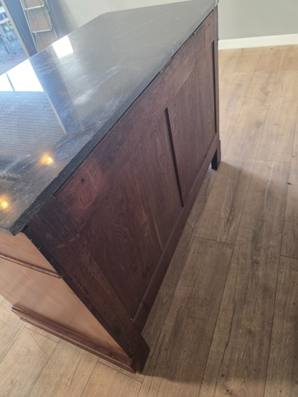 A nineteenth-century French mahogany chest of drawers featuring a dark marble top, flame mahogany drawer fronts, turned wooden knobs, and a plinth base. View XIV