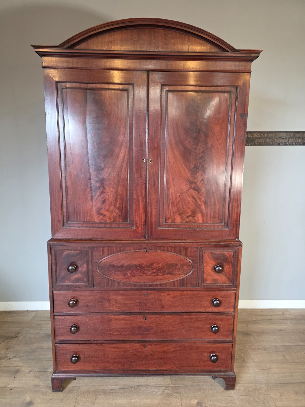 A late George III mahogany linen press featuring a double-door top cupboard under a arched pediment, resting on a lower section with drawers and bracket feet. View III