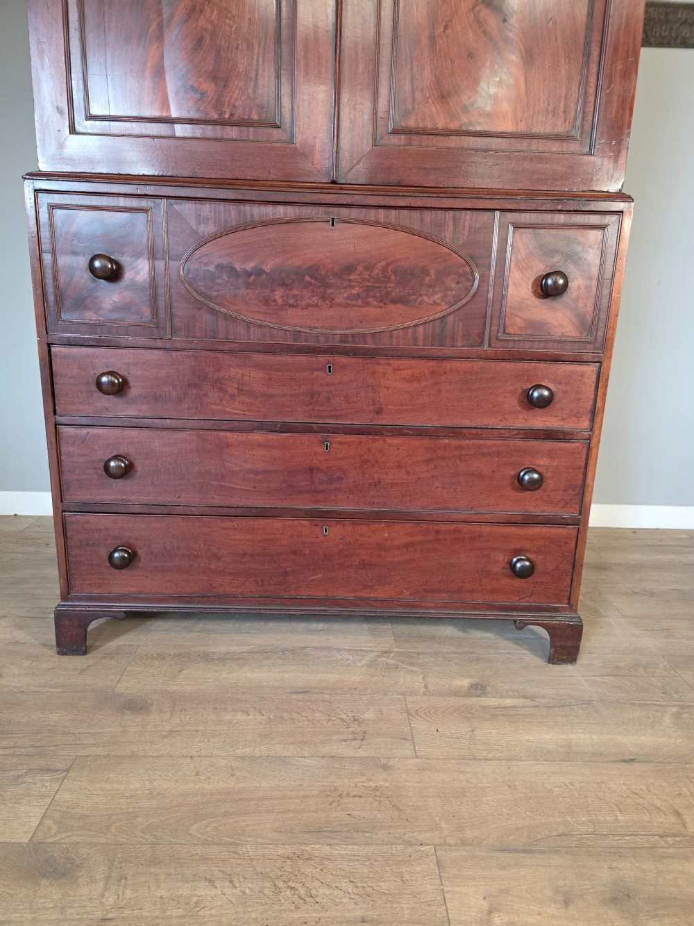 A late George III mahogany linen press featuring a double-door top cupboard under a arched pediment, resting on a lower section with drawers and bracket feet. View IV
