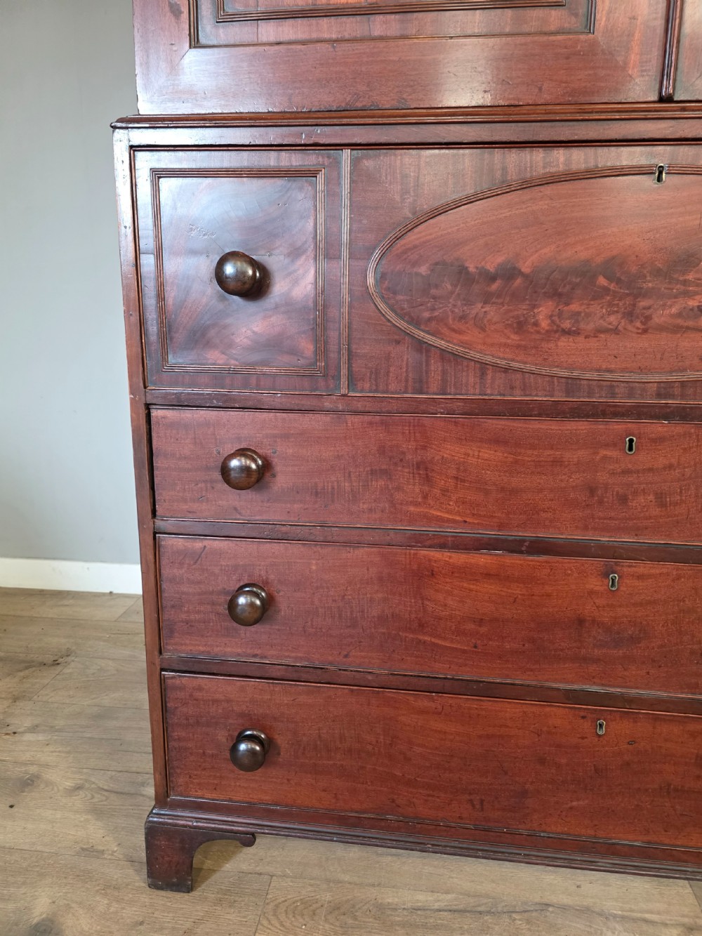 A late George III mahogany linen press featuring a double-door top cupboard under a arched pediment, resting on a lower section with drawers and bracket feet. View V