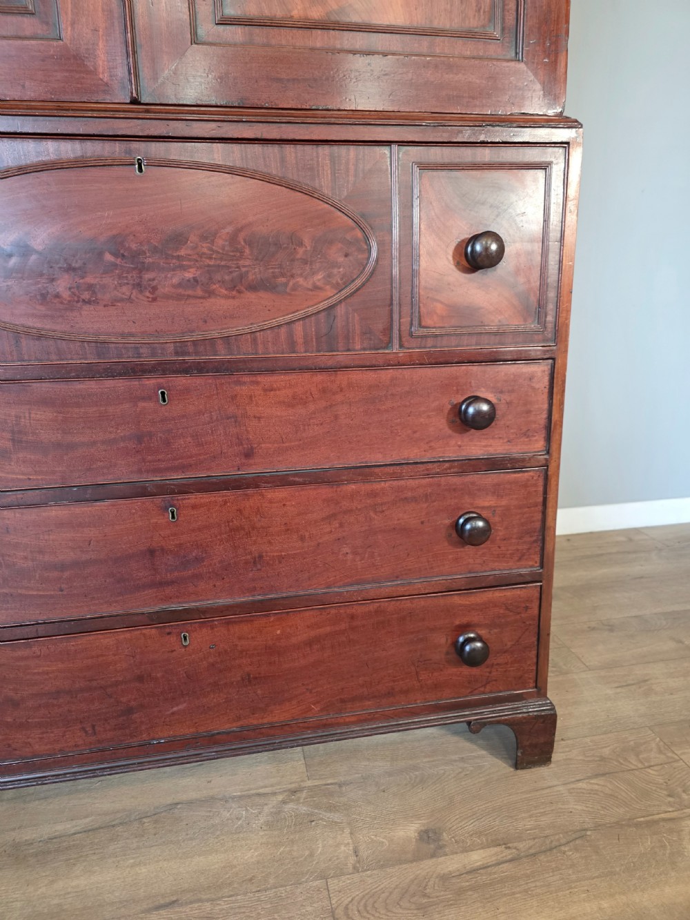 A late George III mahogany linen press featuring a double-door top cupboard under a arched pediment, resting on a lower section with drawers and bracket feet. View VI