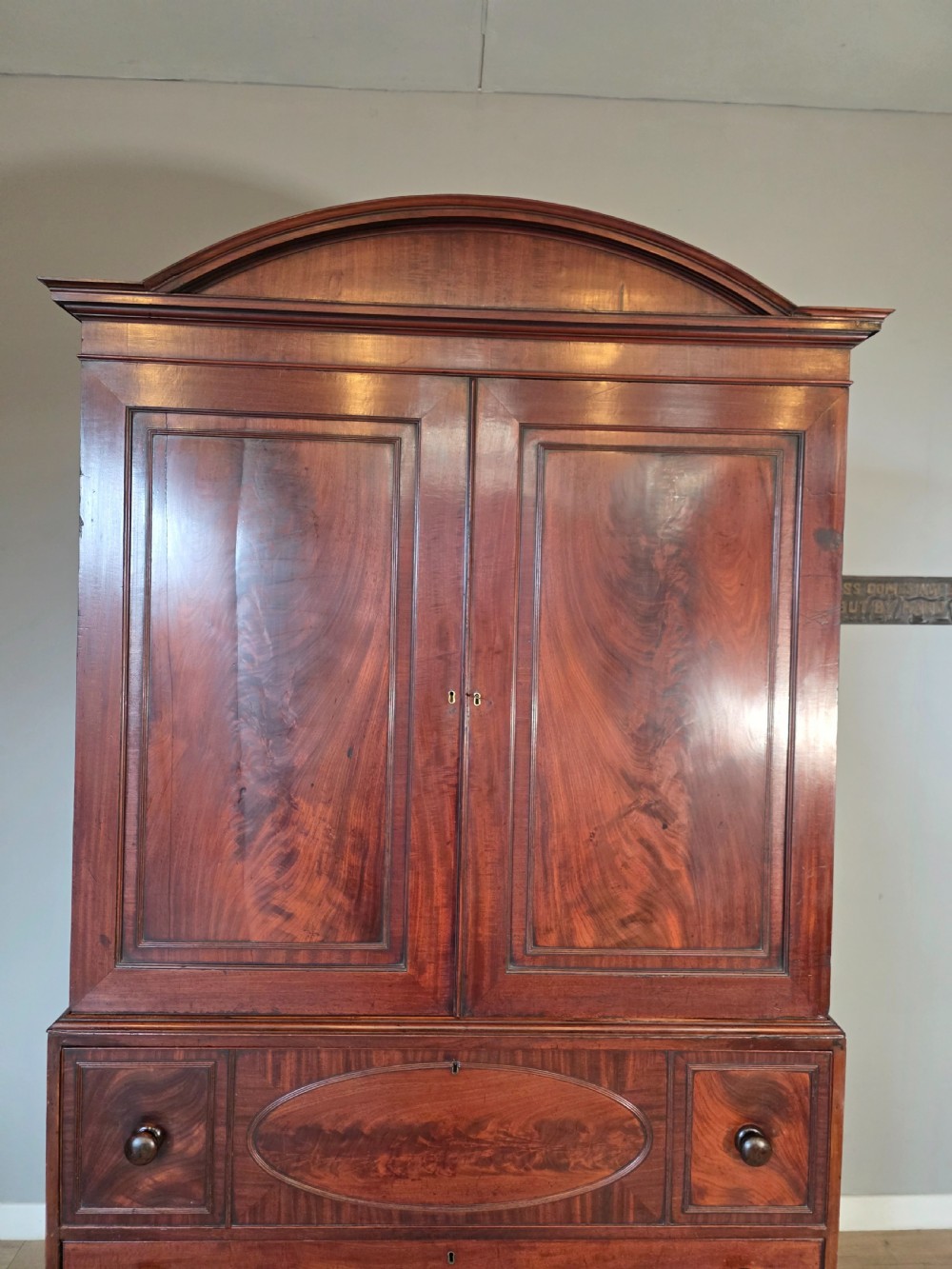 A late George III mahogany linen press featuring a double-door top cupboard under a arched pediment, resting on a lower section with drawers and bracket feet. View VII