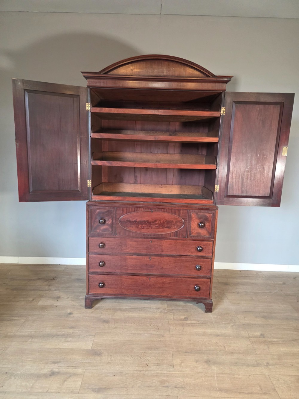 A late George III mahogany linen press featuring a double-door top cupboard under a arched pediment, resting on a lower section with drawers and bracket feet. View VIII