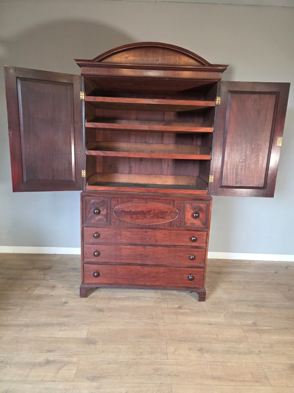 A late George III mahogany linen press featuring a double-door top cupboard under a arched pediment, resting on a lower section with drawers and bracket feet. View IX