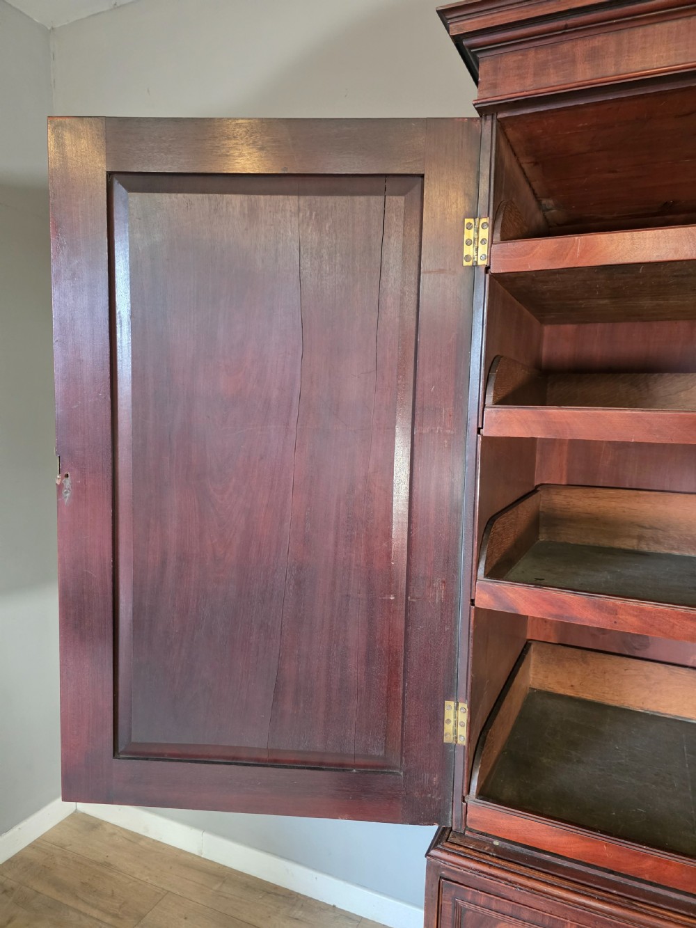 A late George III mahogany linen press featuring a double-door top cupboard under a arched pediment, resting on a lower section with drawers and bracket feet. View X