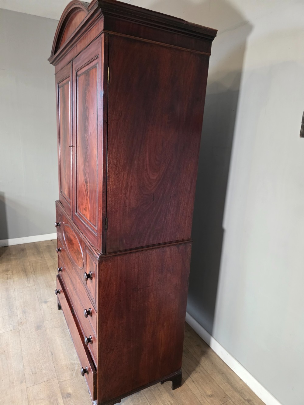 A late George III mahogany linen press featuring a double-door top cupboard under a arched pediment, resting on a lower section with drawers and bracket feet. View XVI