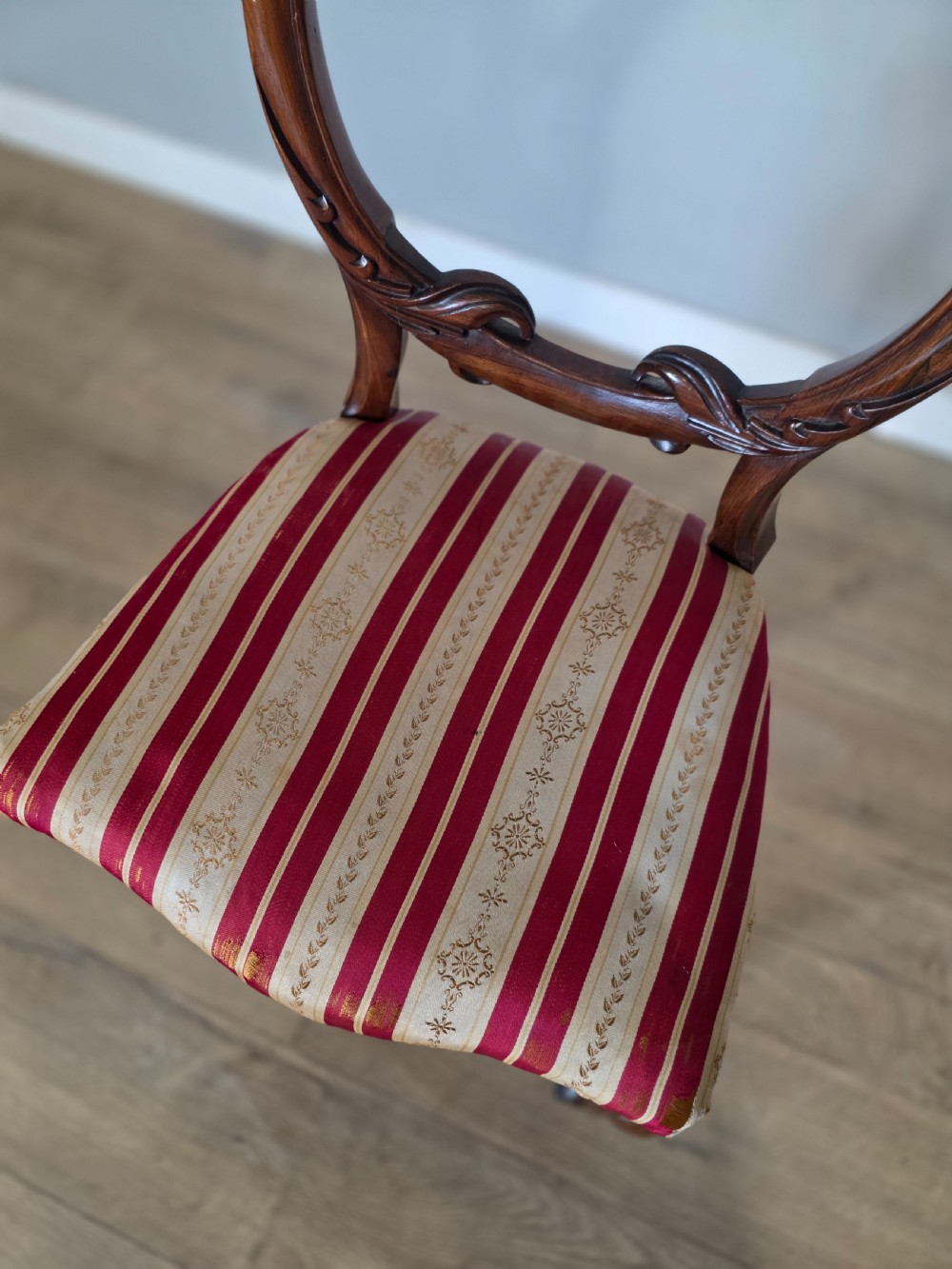 A set of six Victorian rosewood dining chairs featuring open balloon backs, carved waist rails, cabriole legs, and red and gold striped upholstered seats. View VII