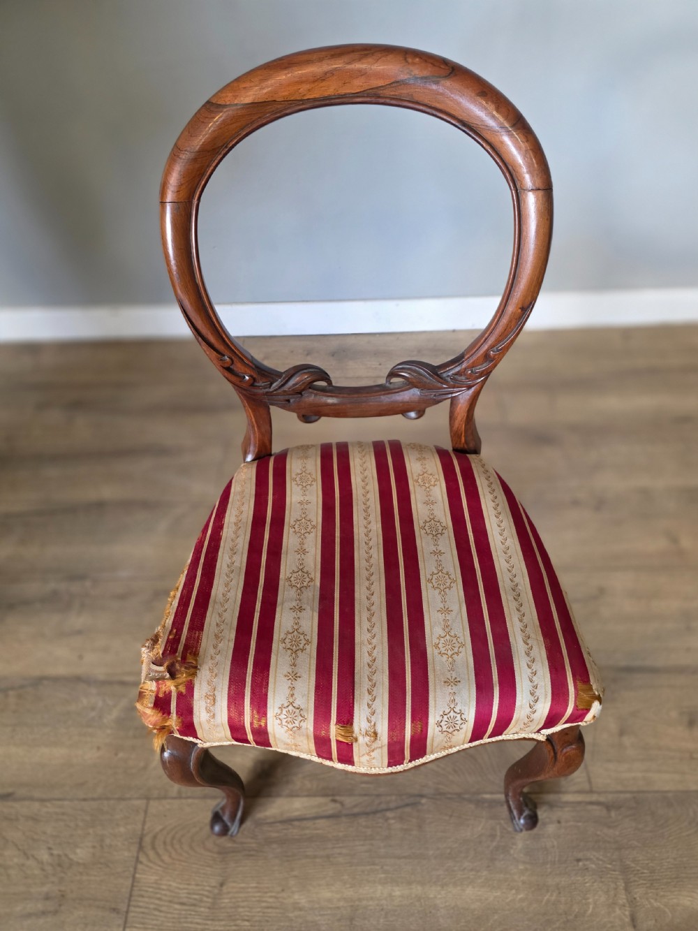 A set of six Victorian rosewood dining chairs featuring open balloon backs, carved waist rails, cabriole legs, and red and gold striped upholstered seats. View XI