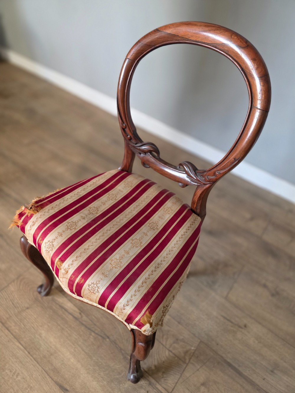 A set of six Victorian rosewood dining chairs featuring open balloon backs, carved waist rails, cabriole legs, and red and gold striped upholstered seats. View XIII