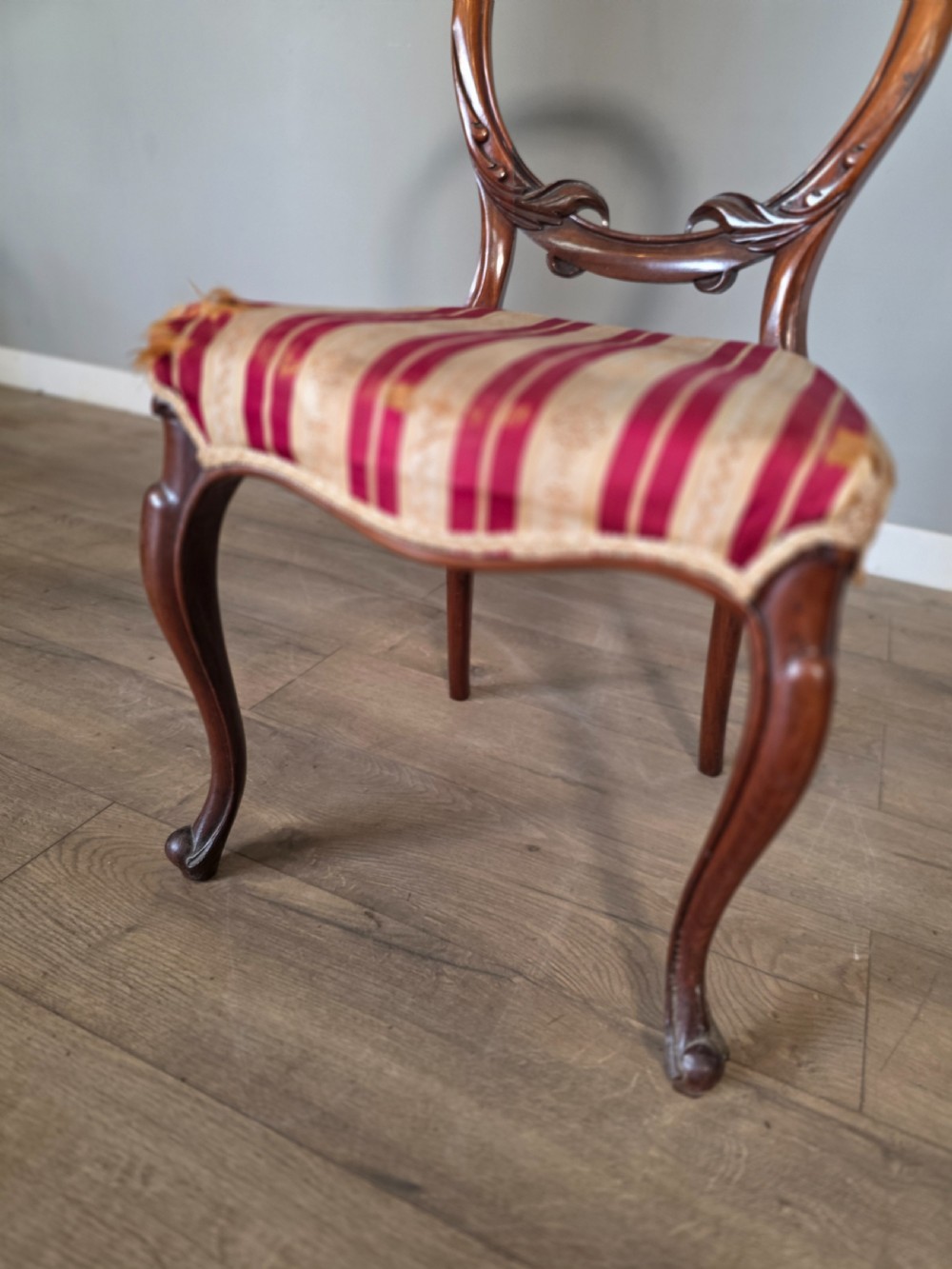 A set of six Victorian rosewood dining chairs featuring open balloon backs, carved waist rails, cabriole legs, and red and gold striped upholstered seats. View XIV