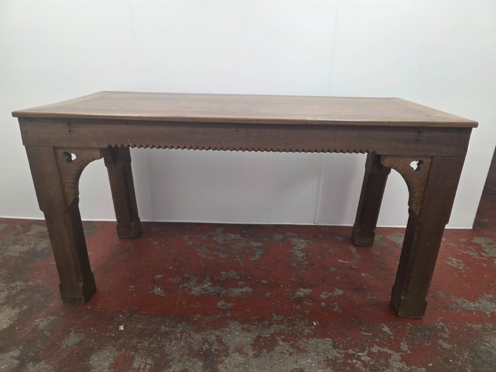 A rectangular dark oak console table featuring a notched dentil apron, carved corner spandrels, and sturdy chamfered legs. View II