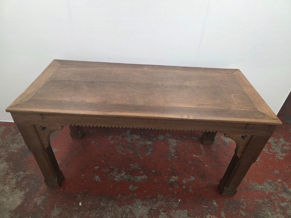 A rectangular dark oak console table featuring a notched dentil apron, carved corner spandrels, and sturdy chamfered legs. View III