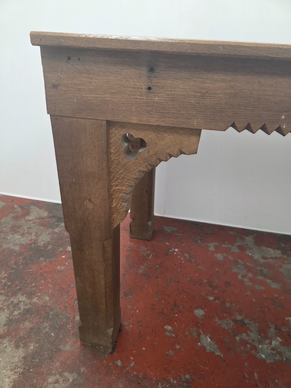 A rectangular dark oak console table featuring a notched dentil apron, carved corner spandrels, and sturdy chamfered legs. View IV