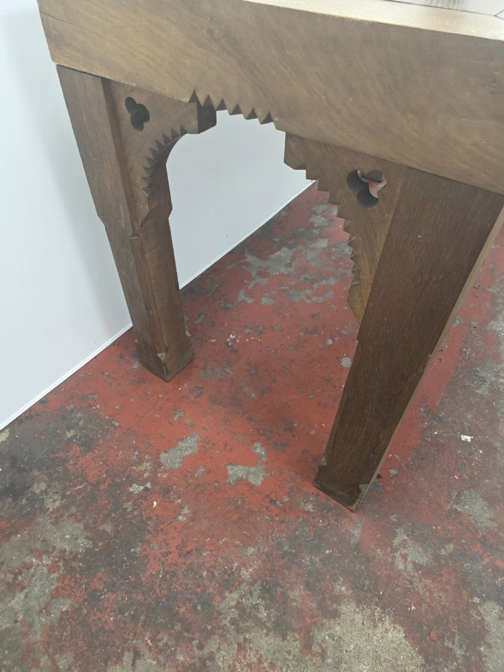 A rectangular dark oak console table featuring a notched dentil apron, carved corner spandrels, and sturdy chamfered legs. View VII