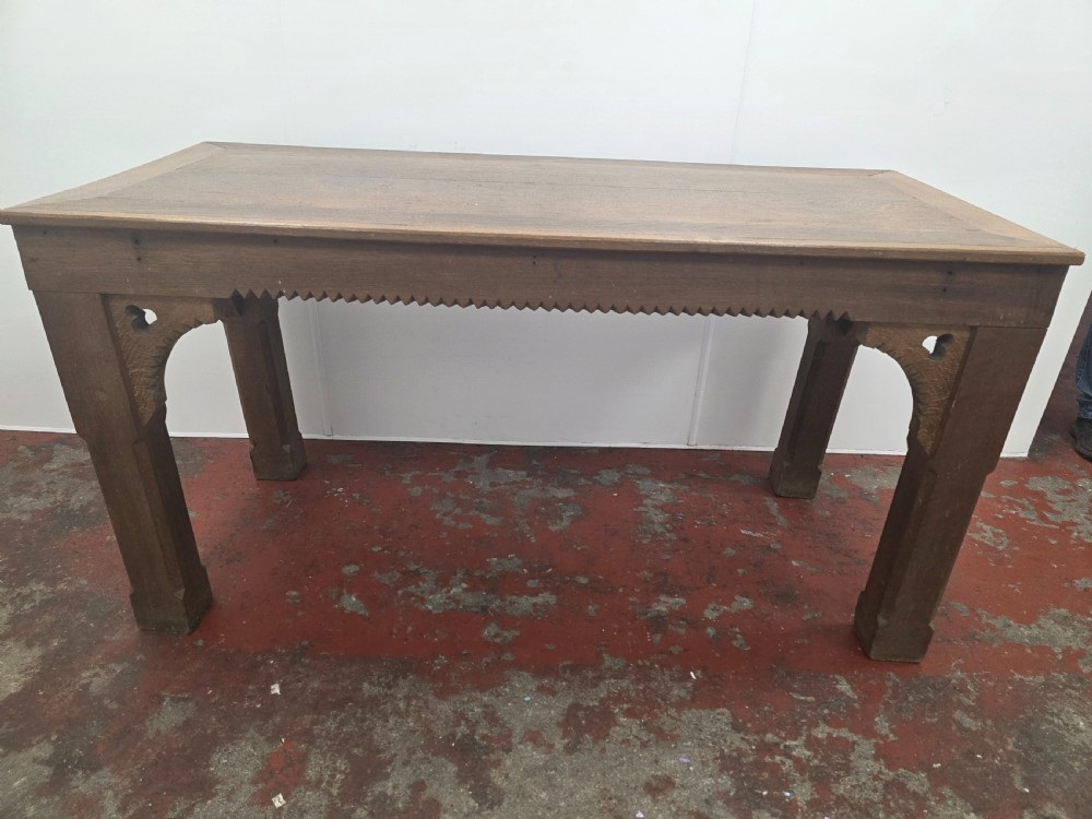 A rectangular dark oak console table featuring a notched dentil apron, carved corner spandrels, and sturdy chamfered legs. View VIII
