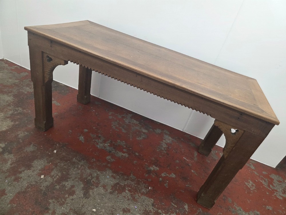 A rectangular dark oak console table featuring a notched dentil apron, carved corner spandrels, and sturdy chamfered legs. View IX