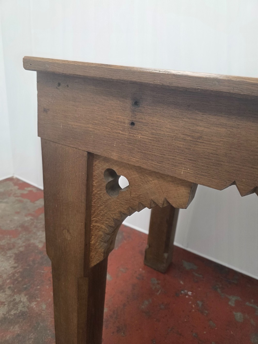 A rectangular dark oak console table featuring a notched dentil apron, carved corner spandrels, and sturdy chamfered legs. View XI