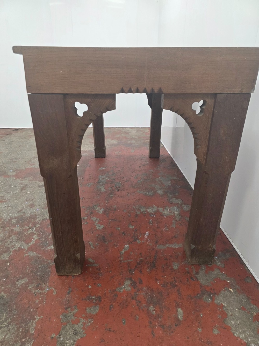 A rectangular dark oak console table featuring a notched dentil apron, carved corner spandrels, and sturdy chamfered legs. View XII