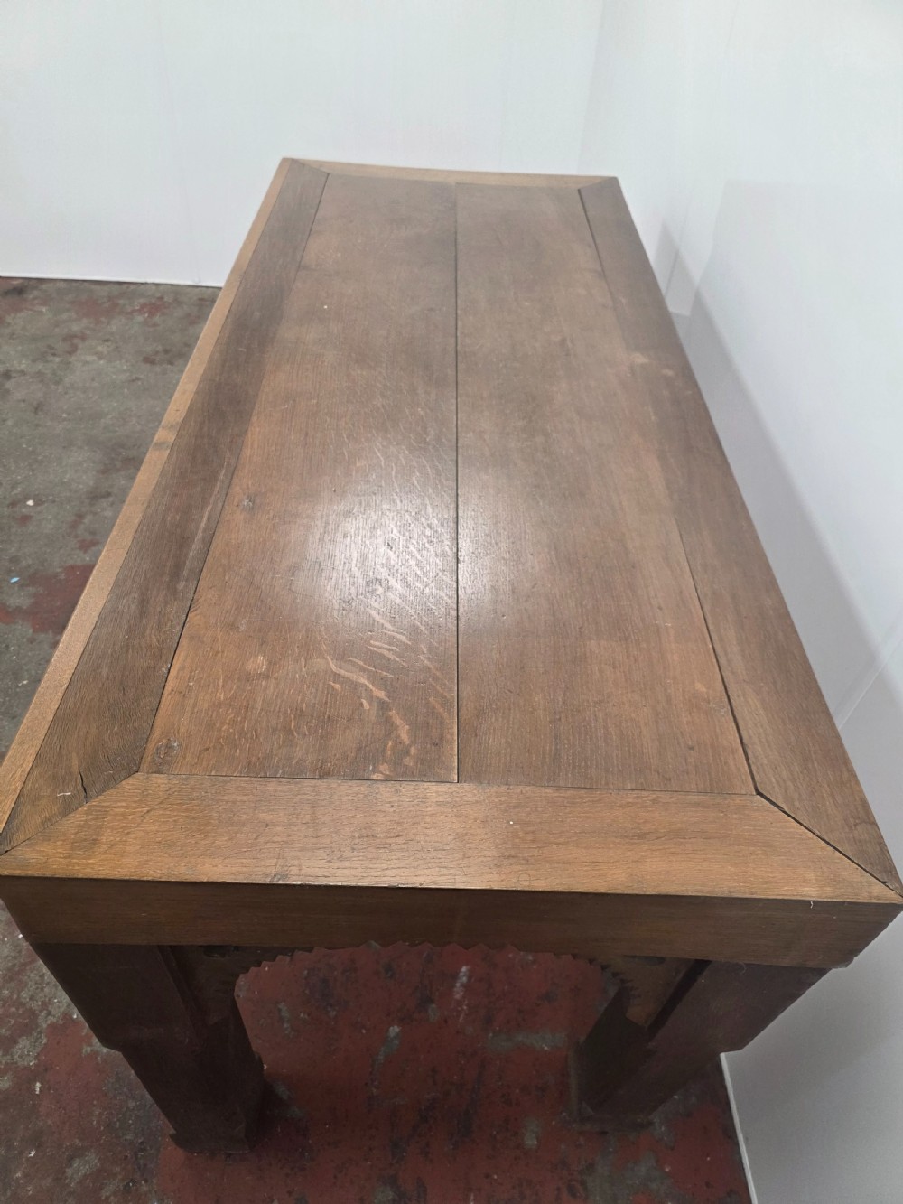 A rectangular dark oak console table featuring a notched dentil apron, carved corner spandrels, and sturdy chamfered legs. View XIII