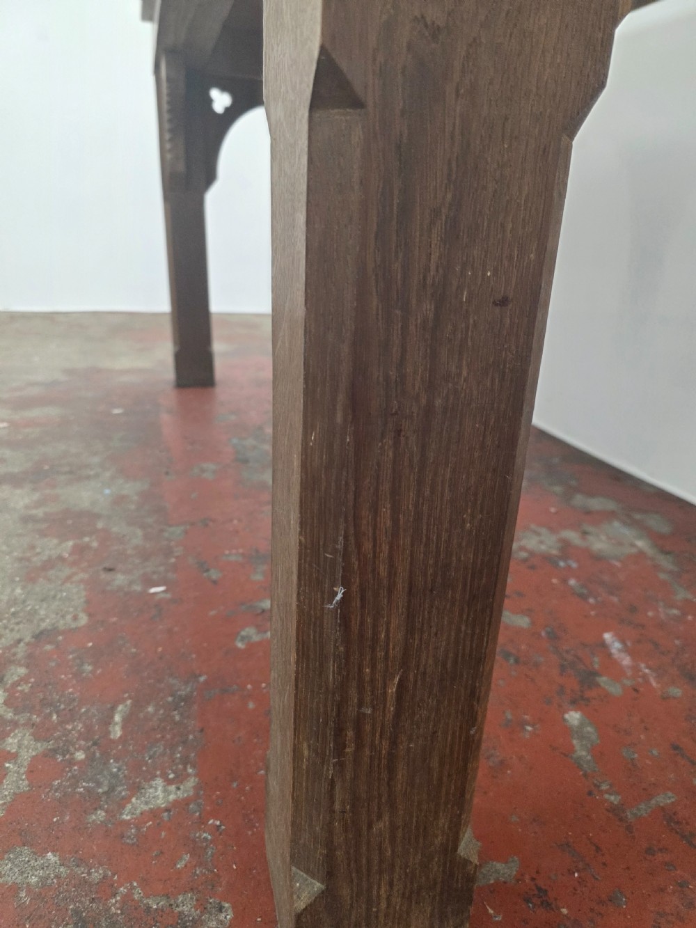 A rectangular dark oak console table featuring a notched dentil apron, carved corner spandrels, and sturdy chamfered legs. View XV
