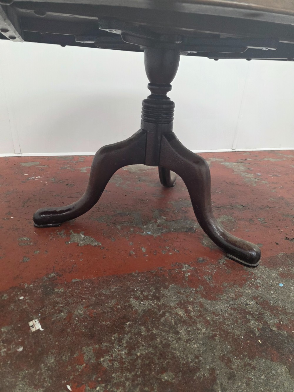 An oval low coffee table featuring a figured burr walnut top set on a dark cast iron tripod base. View V