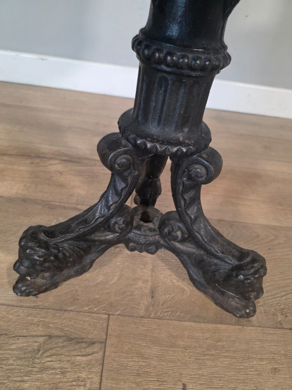 An antique 1890s swivel chair featuring a carved oak backrest, brown leather studded seat, and a cast iron pedestal base. View V