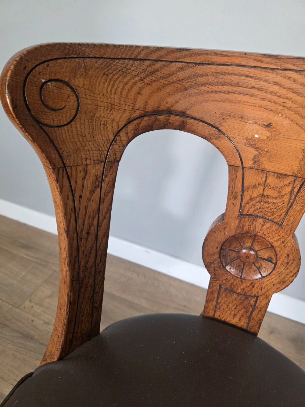 An antique 1890s swivel chair featuring a carved oak backrest, brown leather studded seat, and a cast iron pedestal base. View IX
