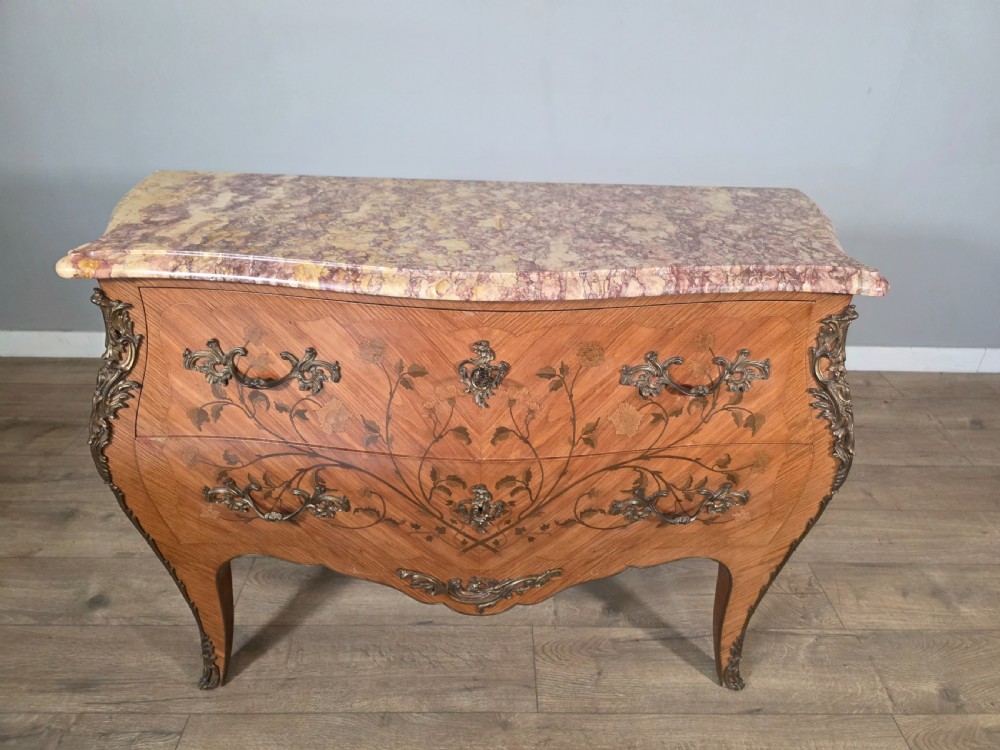 A French Louis XV style bombe commode featuring floral marquetry wood inlays, gilded metal mounts, cabriole legs, and a shaped pink-variegated marble top. View III