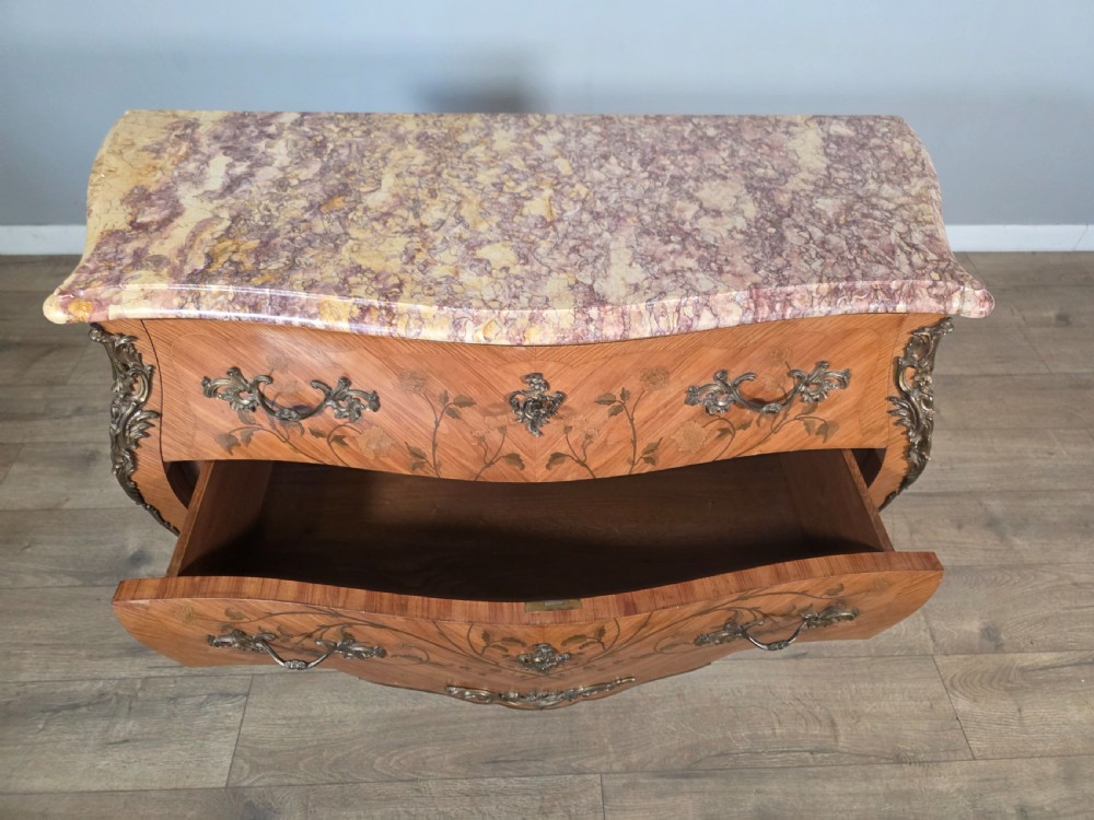 A French Louis XV style bombe commode featuring floral marquetry wood inlays, gilded metal mounts, cabriole legs, and a shaped pink-variegated marble top. View XIV