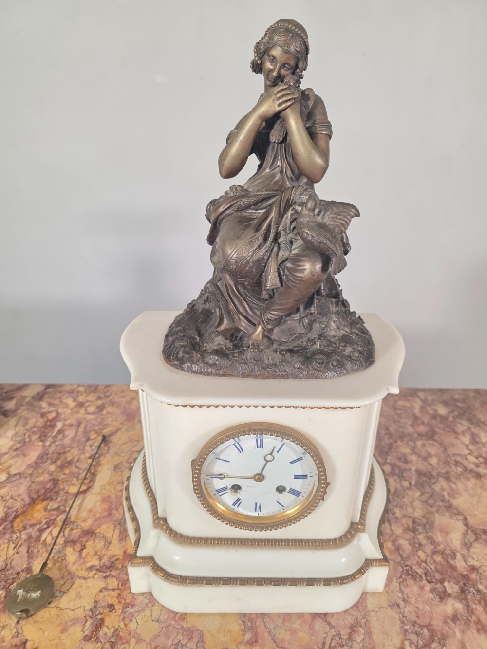A late 19th-century French white marble mantel clock set featuring a patinated bronze seated female figure surmount, flanked by two matching marble tazze. View V