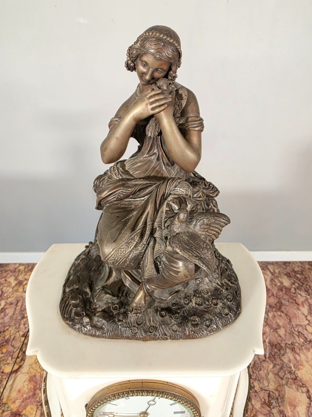 A late 19th-century French white marble mantel clock set featuring a patinated bronze seated female figure surmount, flanked by two matching marble tazze. View VI