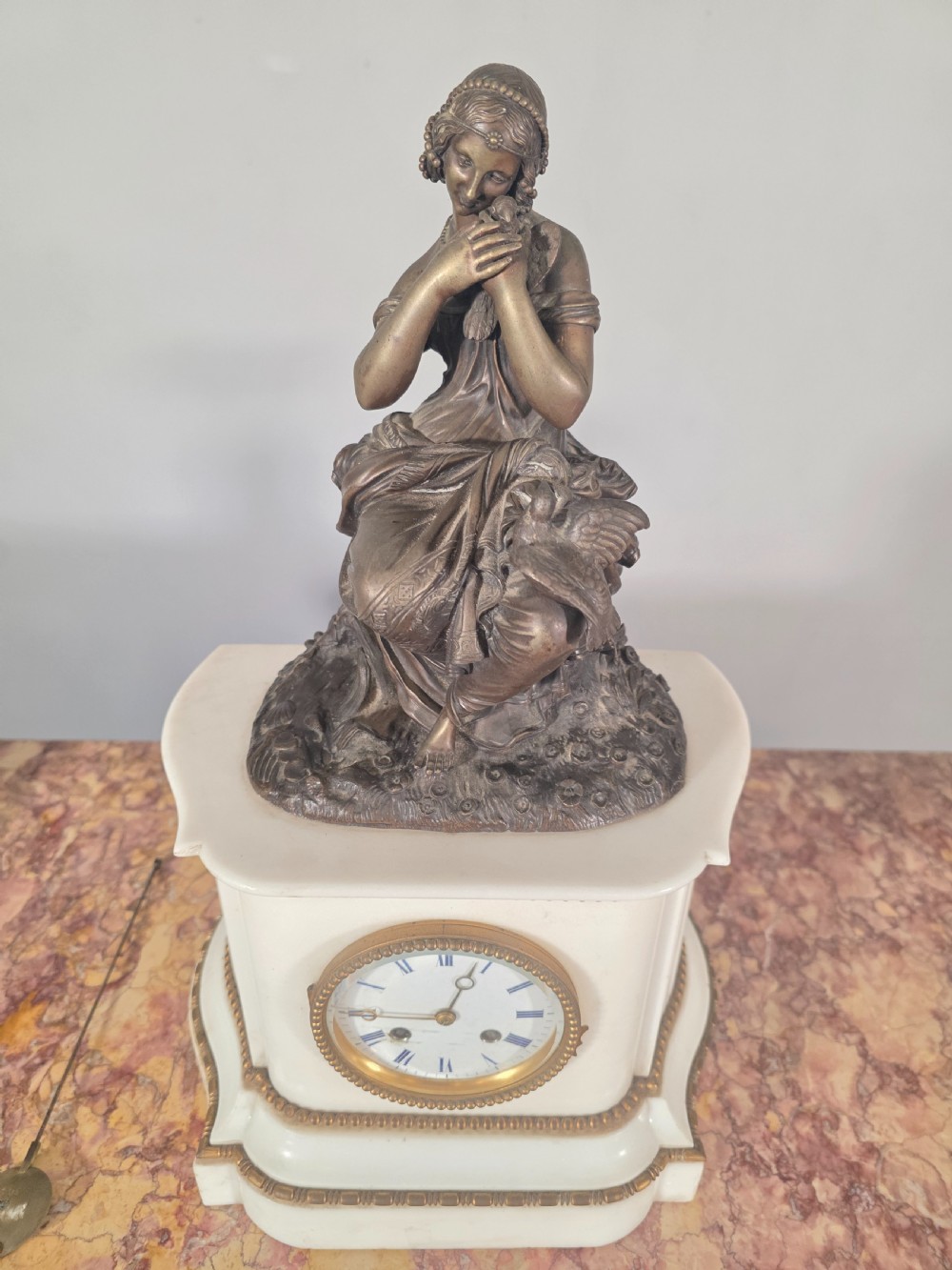 A late 19th-century French white marble mantel clock set featuring a patinated bronze seated female figure surmount, flanked by two matching marble tazze. View VIII