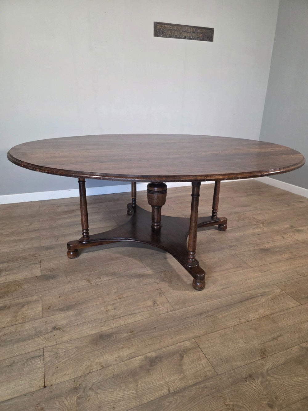 A large antique oval oak dining table featuring turned legs and a central stretcher base. View II