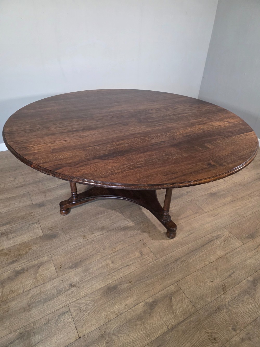 A large antique oval oak dining table featuring turned legs and a central stretcher base. View IV