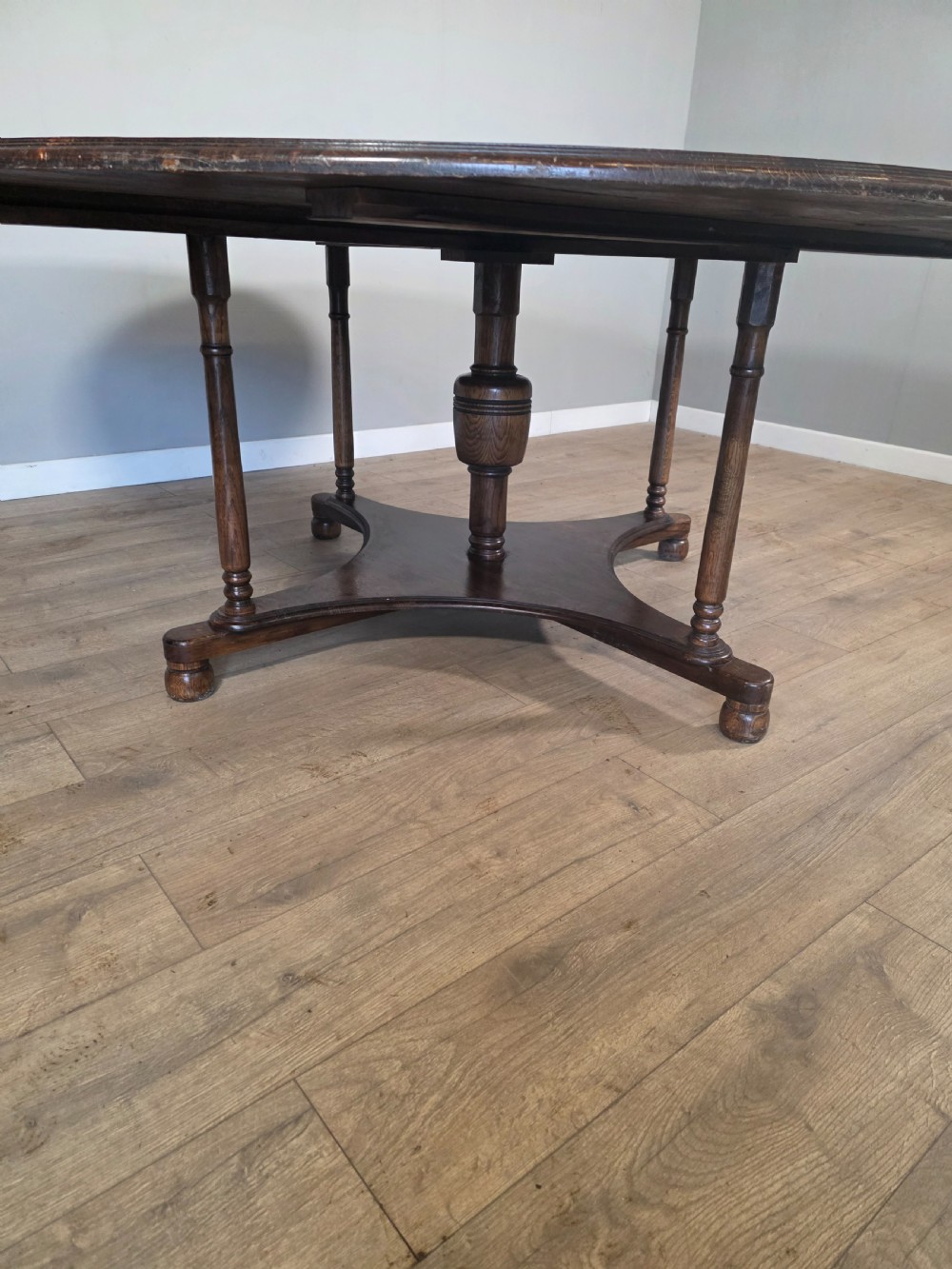 A large antique oval oak dining table featuring turned legs and a central stretcher base. View X