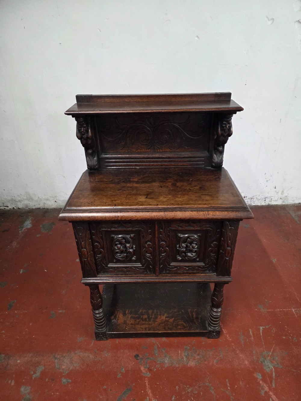 A dark brown late Victorian carved oak buffet featuring fielded panels, figural corbels, a tiered plate rack, and a lower undertier shelf. View III