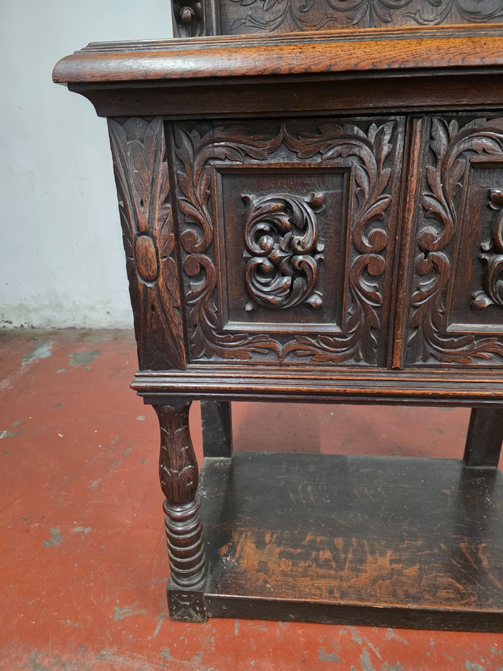 A dark brown late Victorian carved oak buffet featuring fielded panels, figural corbels, a tiered plate rack, and a lower undertier shelf. View VII