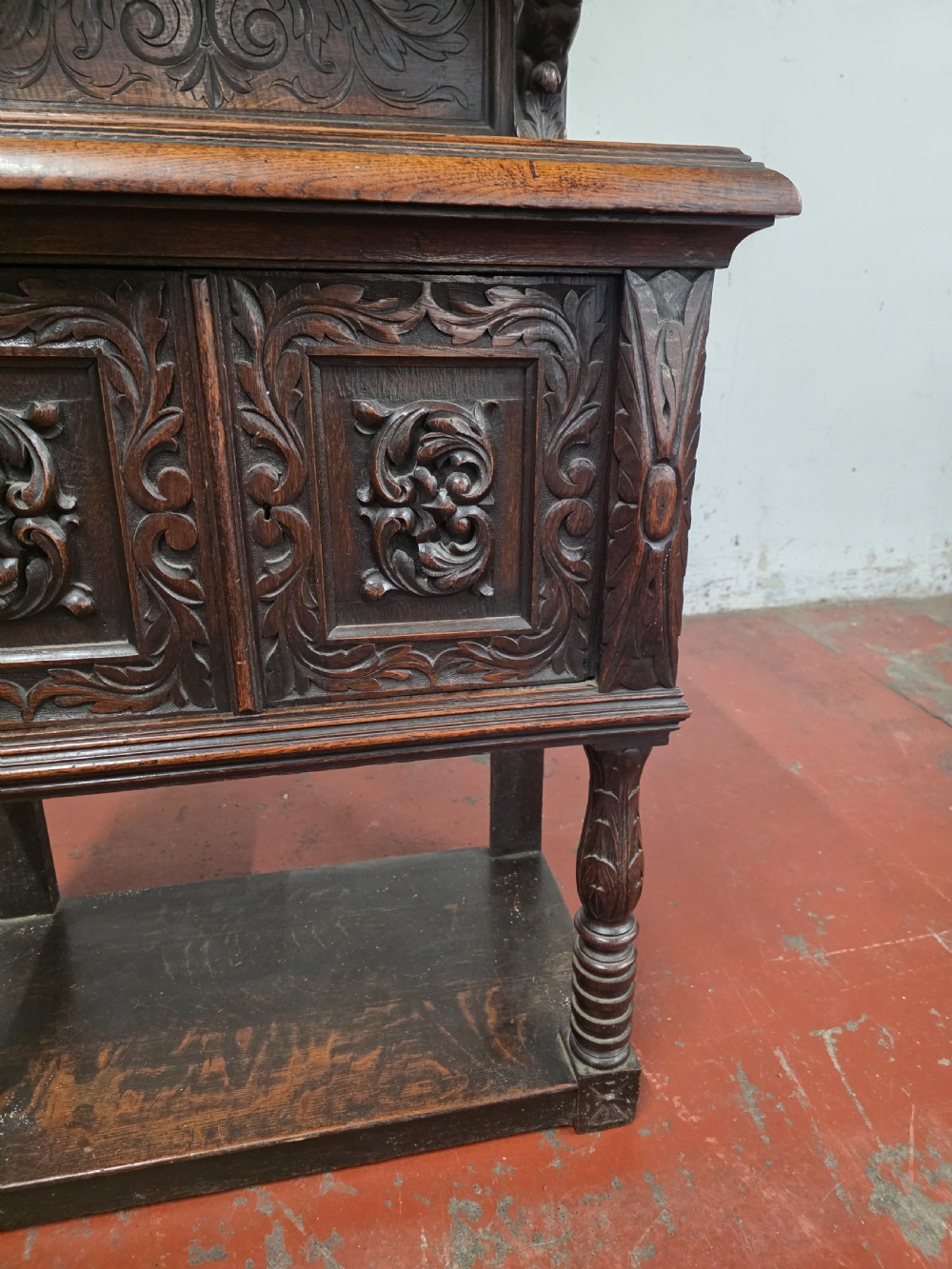 A dark brown late Victorian carved oak buffet featuring fielded panels, figural corbels, a tiered plate rack, and a lower undertier shelf. View VIII