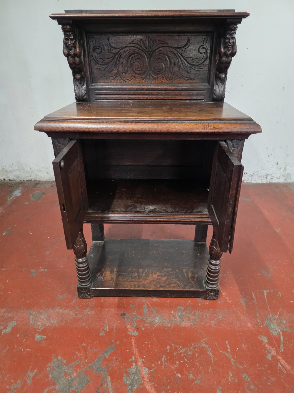 A dark brown late Victorian carved oak buffet featuring fielded panels, figural corbels, a tiered plate rack, and a lower undertier shelf. View X