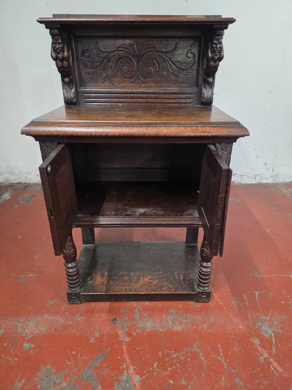 A dark brown late Victorian carved oak buffet featuring fielded panels, figural corbels, a tiered plate rack, and a lower undertier shelf. View XI