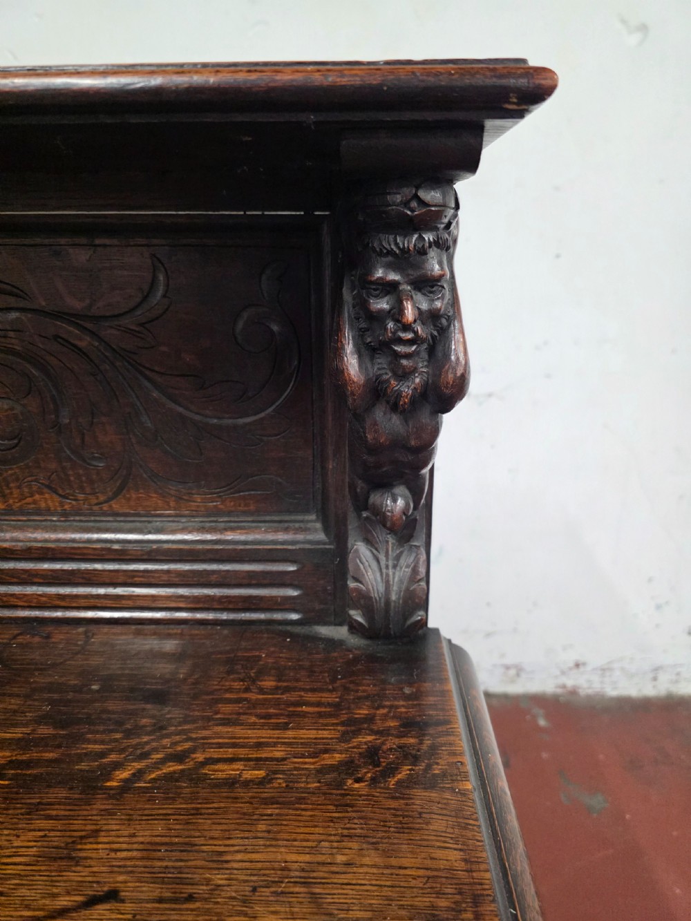 A dark brown late Victorian carved oak buffet featuring fielded panels, figural corbels, a tiered plate rack, and a lower undertier shelf. View XIV