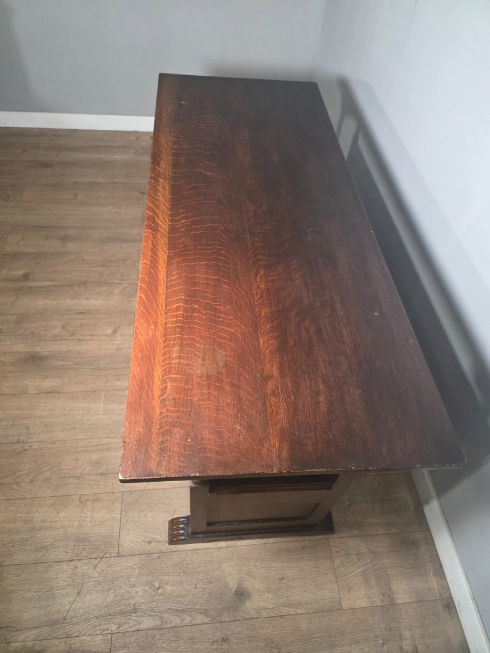 A 1920s carved dark oak monks bench featuring a high panelled backrest, turned arm supports, and a lower storage box base. View XII