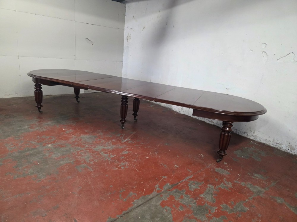 A large William IV mahogany extending banquet dining table featuring rounded ends, multiple insert leaves, and turned legs on brass castors. View VI