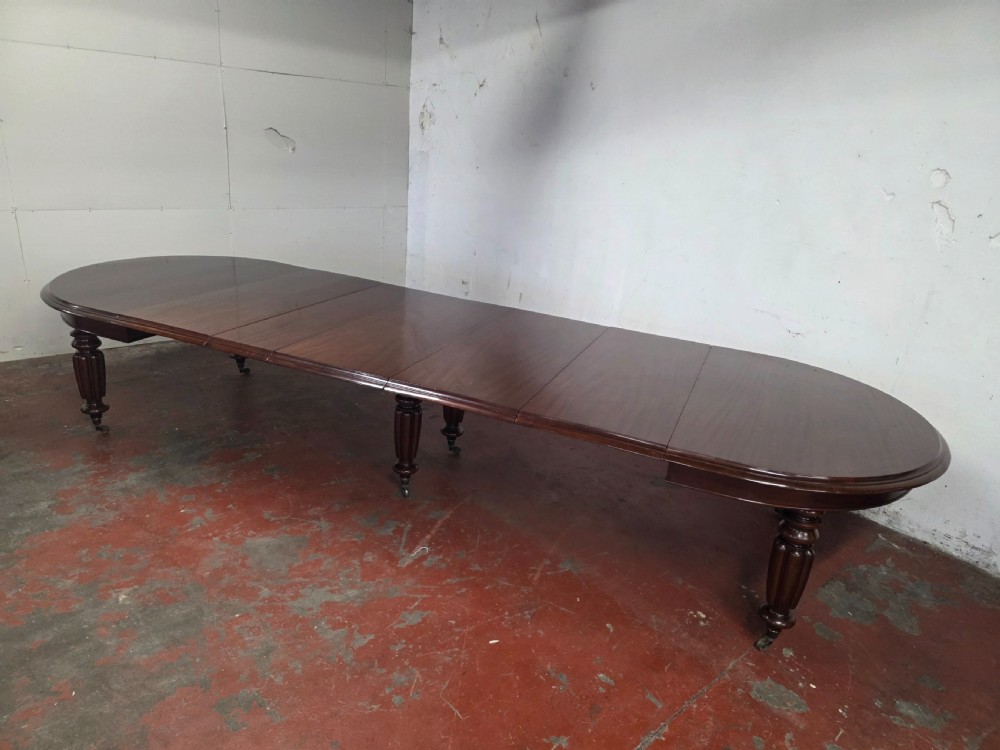 A large William IV mahogany extending banquet dining table featuring rounded ends, multiple insert leaves, and turned legs on brass castors. View VII