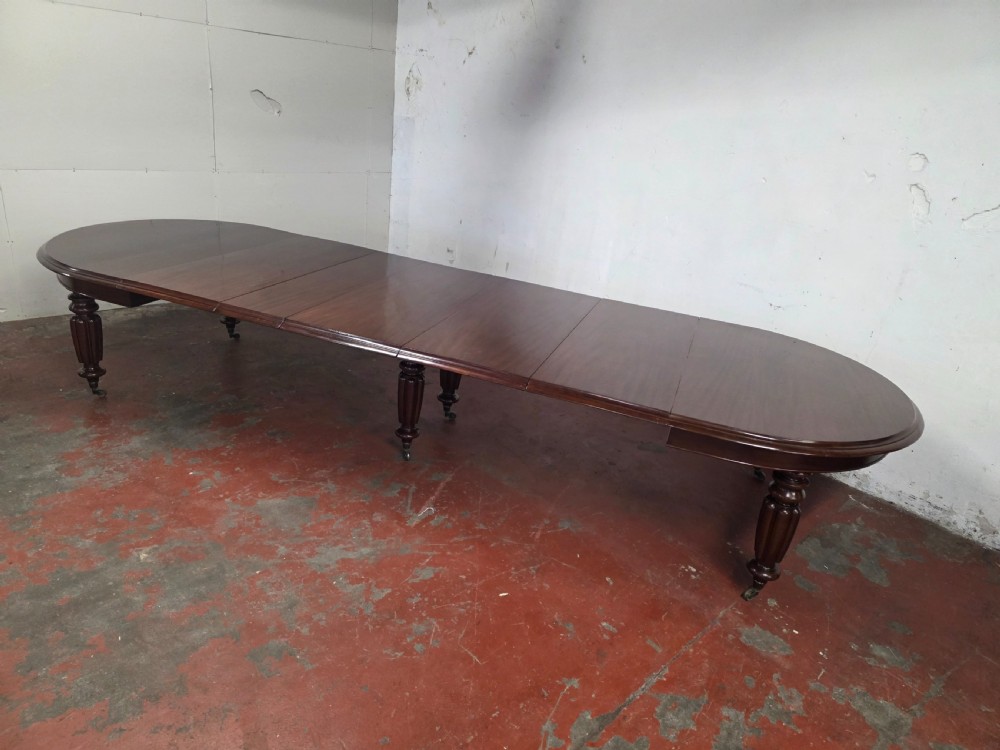 A large William IV mahogany extending banquet dining table featuring rounded ends, multiple insert leaves, and turned legs on brass castors. View X