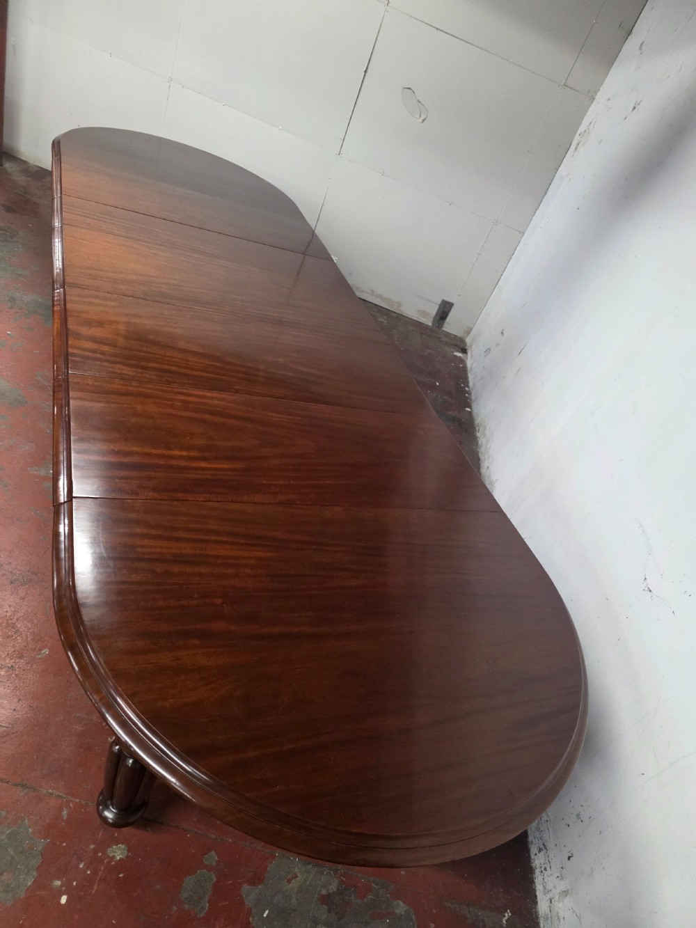 A large William IV mahogany extending banquet dining table featuring rounded ends, multiple insert leaves, and turned legs on brass castors. View XI