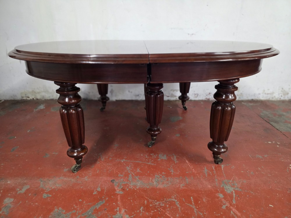 A large William IV mahogany extending banquet dining table featuring rounded ends, multiple insert leaves, and turned legs on brass castors. View XIV