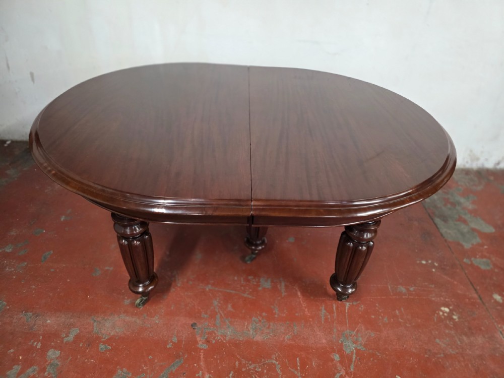 A large William IV mahogany extending banquet dining table featuring rounded ends, multiple insert leaves, and turned legs on brass castors. View XVIII