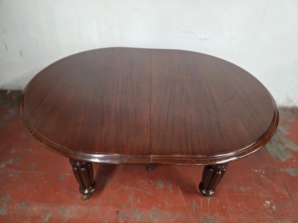 A large William IV mahogany extending banquet dining table featuring rounded ends, multiple insert leaves, and turned legs on brass castors. View XIX