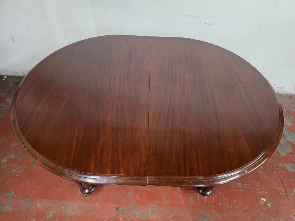 A large William IV mahogany extending banquet dining table featuring rounded ends, multiple insert leaves, and turned legs on brass castors. View XXII